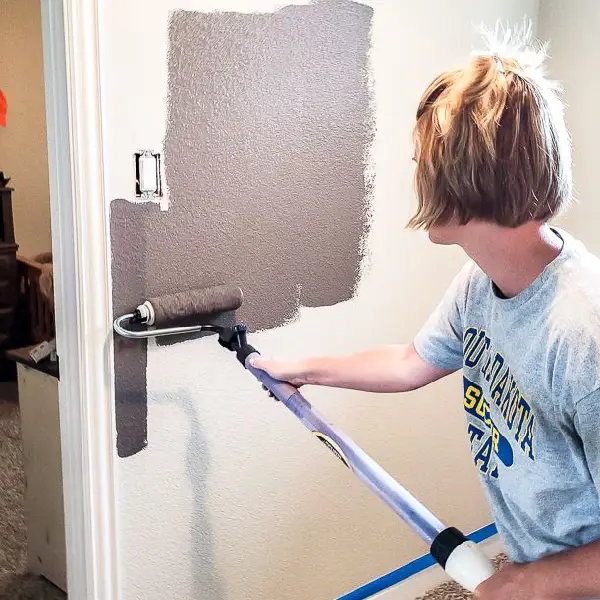 woman painting wall with paint roller