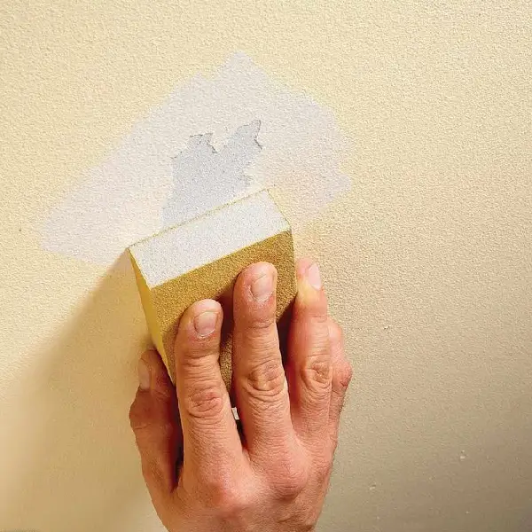 man sanding the wall